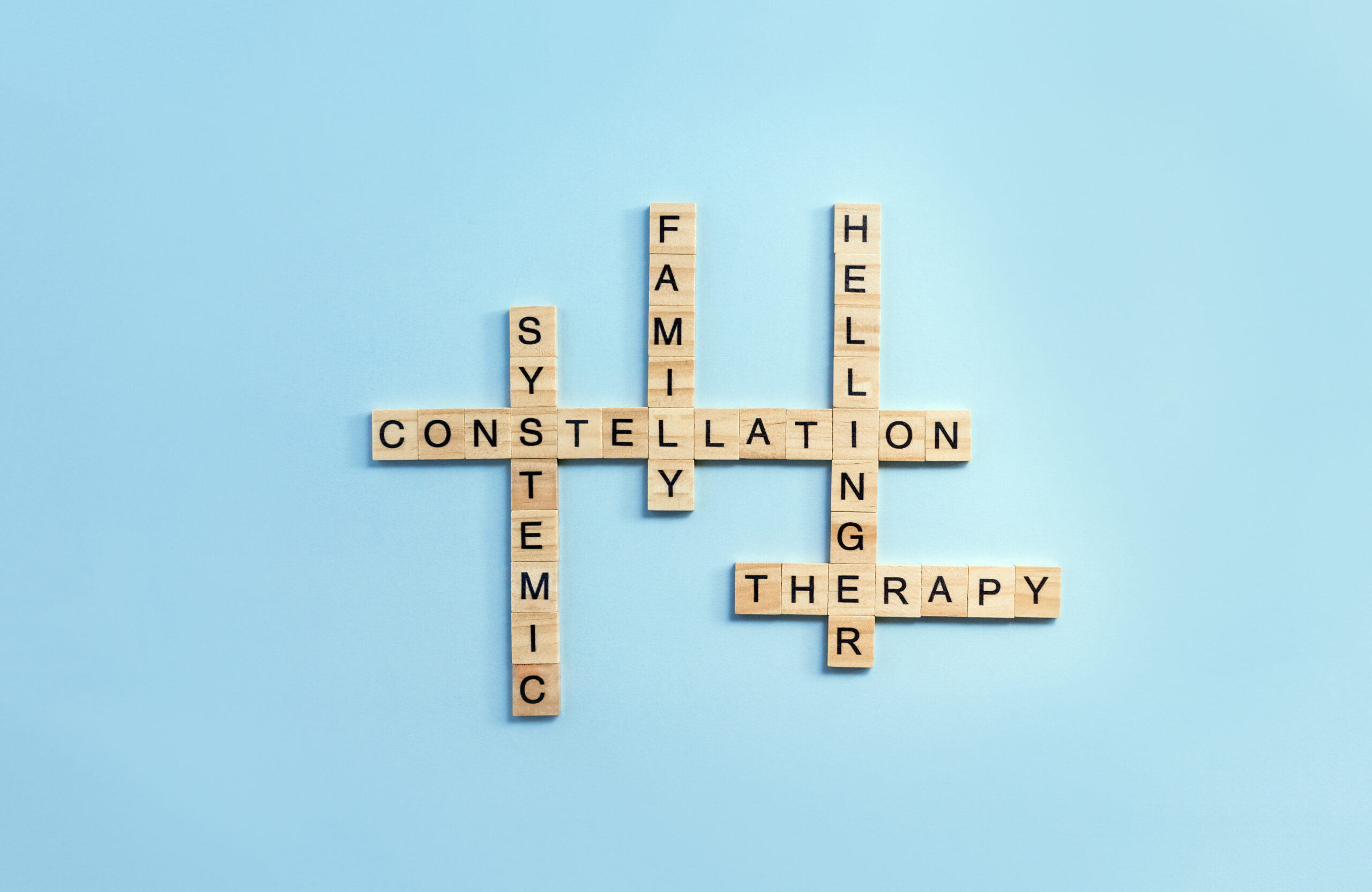 Crossword made from wooden blocks with letters on the theme of family constellations on blue background. Alternative method of psychotherapy. Selective focus Crossword made from wooden blocks with letters on the theme of family constellations on blue background. Alternative method of psychotherapy. Selective focus